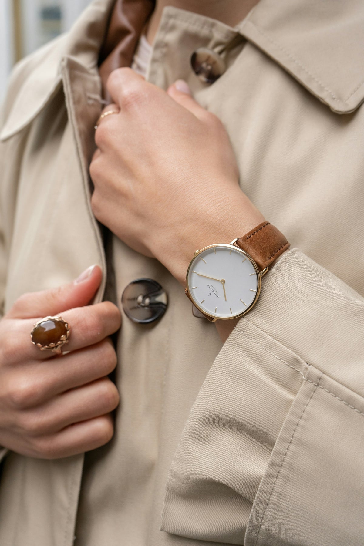 Reloj dorado con correa de piel en la muñeca