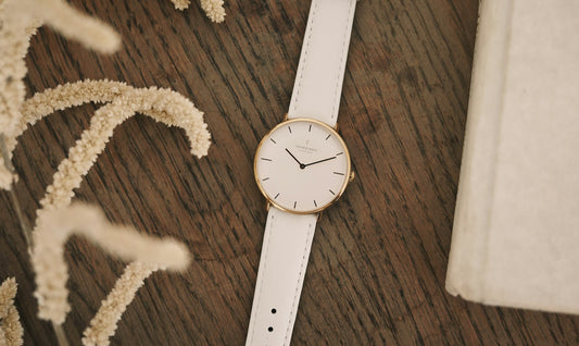 Reloj minimalista con caja dorada, esfera blanca y correa blanca