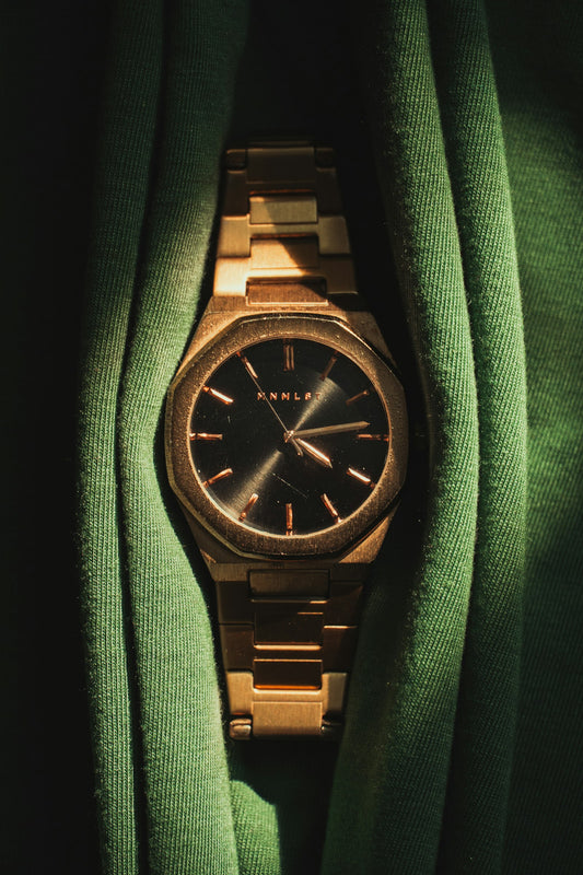 Reloj de caja octogonal en tono dorado con esfera negra y brazalete dorado
